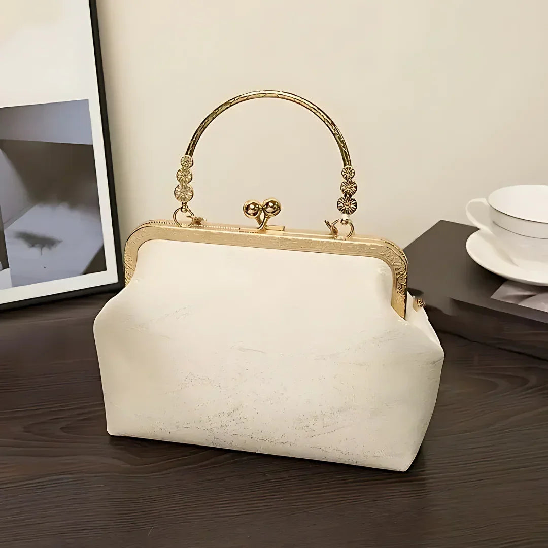 Vintage white handbag with gold metal handle on dark wooden table