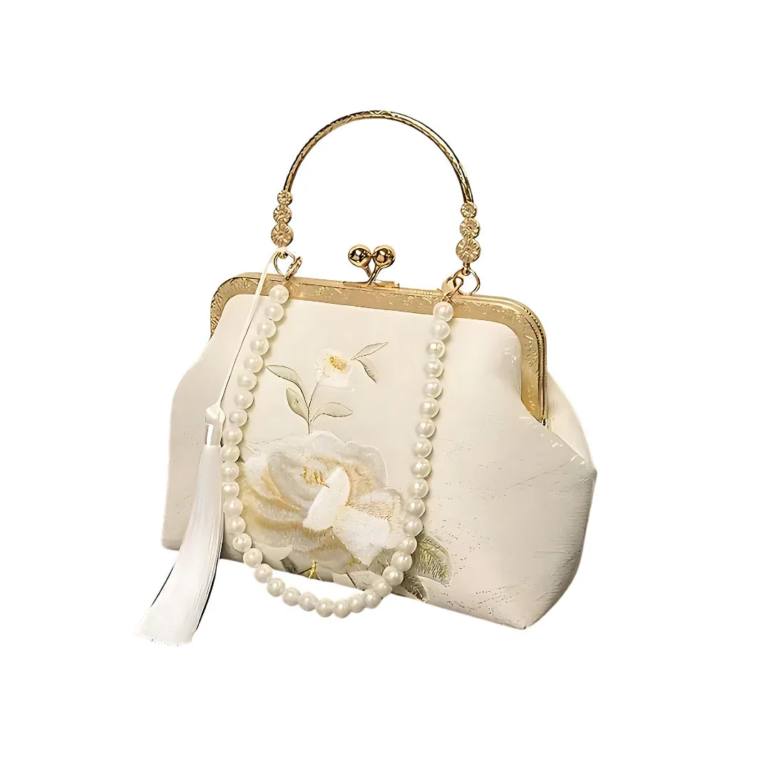 Elegant white floral purse with pearl handle, gold frame, and tassel on white background