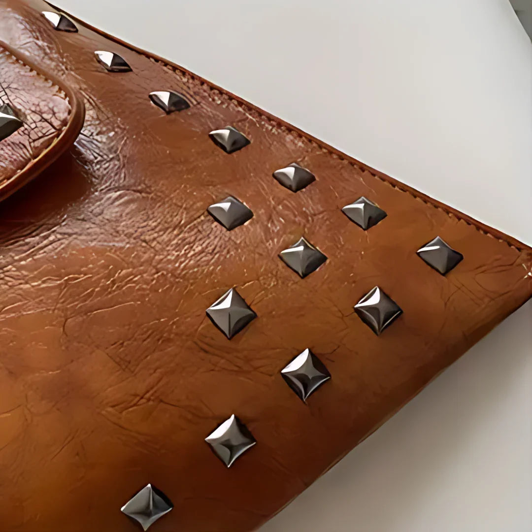 Brown leather clutch with silver square studs on white background