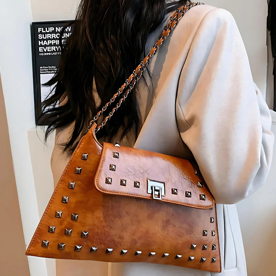 Brown leather shoulder bag with metal studs, chain strap, and geometric clasp