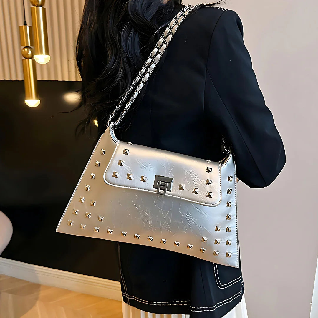 Woman in black blazer carrying metallic silver studded shoulder bag with chain strap