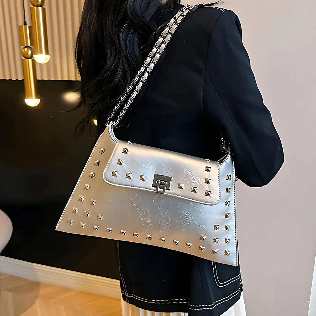 Woman in black blazer carrying metallic silver studded shoulder bag with chain strap