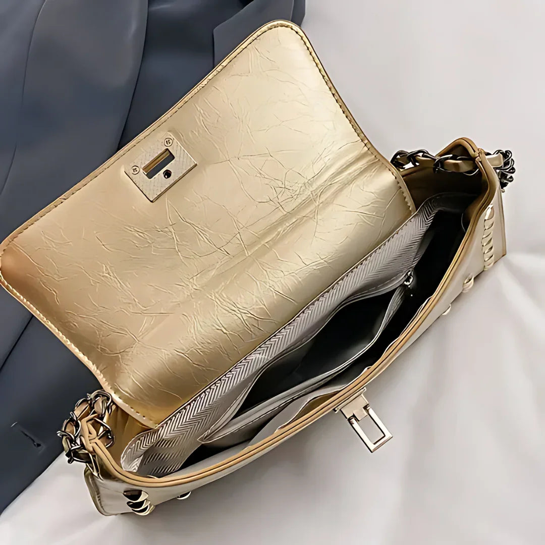 Beige leather crossbody purse with gold hardware and spacious interior, on white fabric