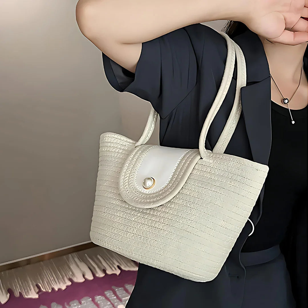 Woman holding cream woven handbag with pearl clasp, stylish accessory fashion