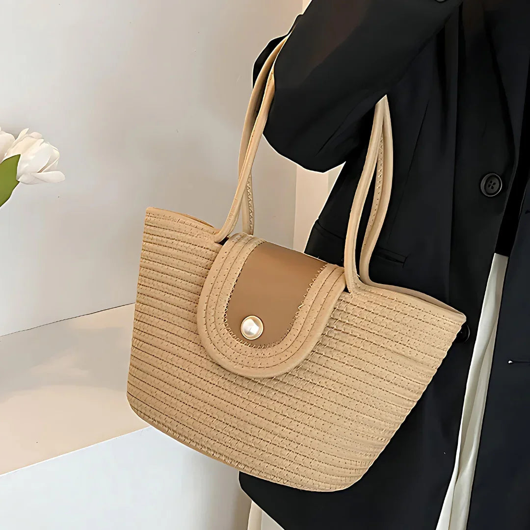 Woman wearing black blazer holding beige woven tote bag with button-flap closure