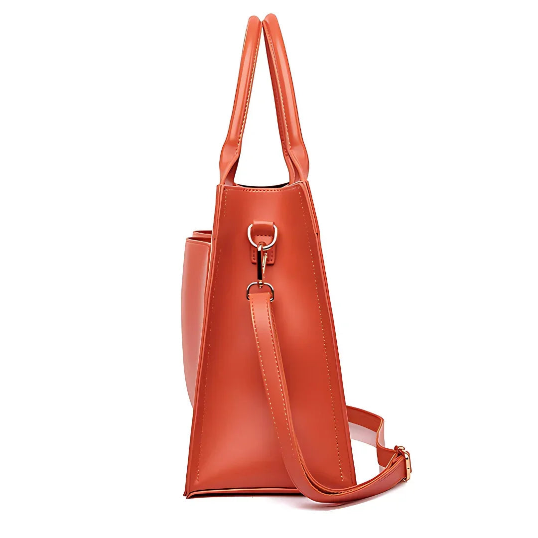 Side view of orange leather tote bag with shoulder strap and double handles on white background