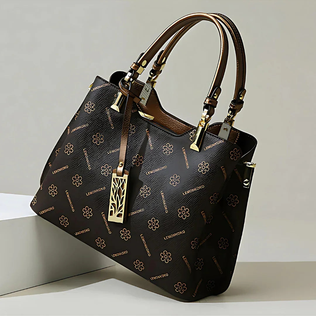 Elegant brown designer handbag with gold accents and floral pattern on a neutral background