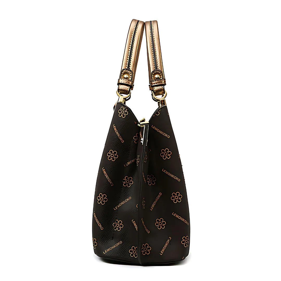 Side view of a black designer handbag with gold floral pattern and dual handles