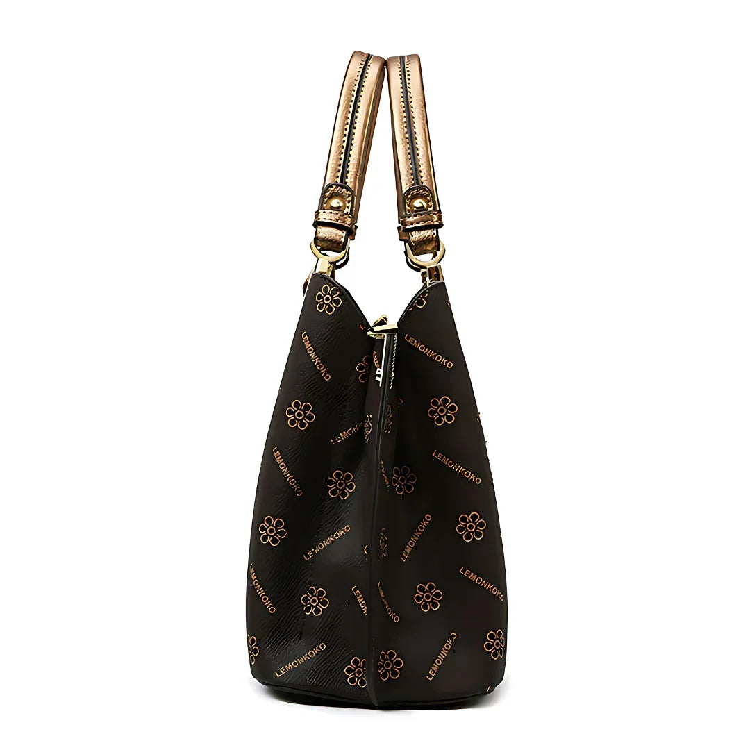Side view of a black designer handbag with gold floral pattern and dual handles
