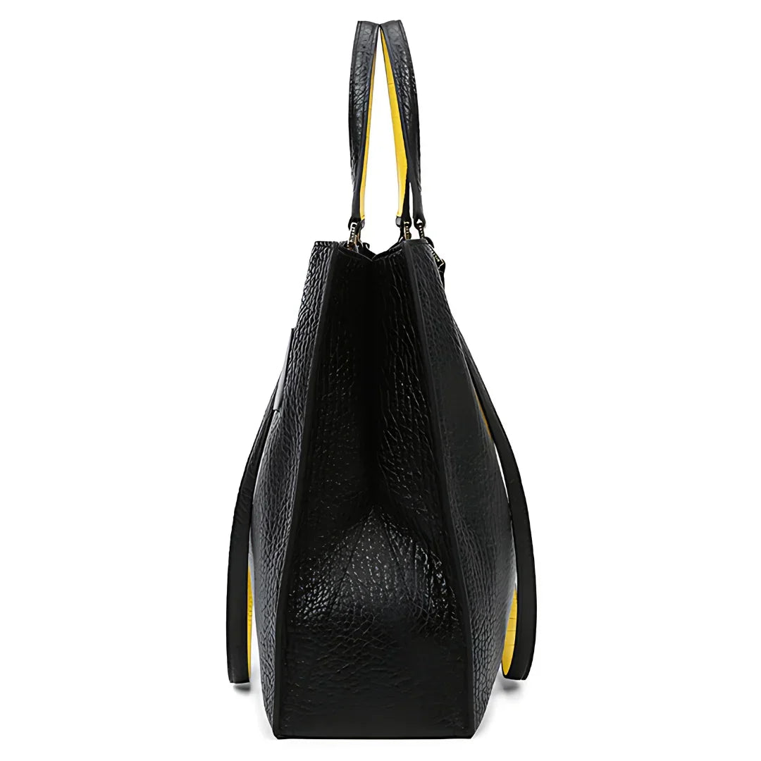 Side view of black textured leather tote bag with yellow interior on white background