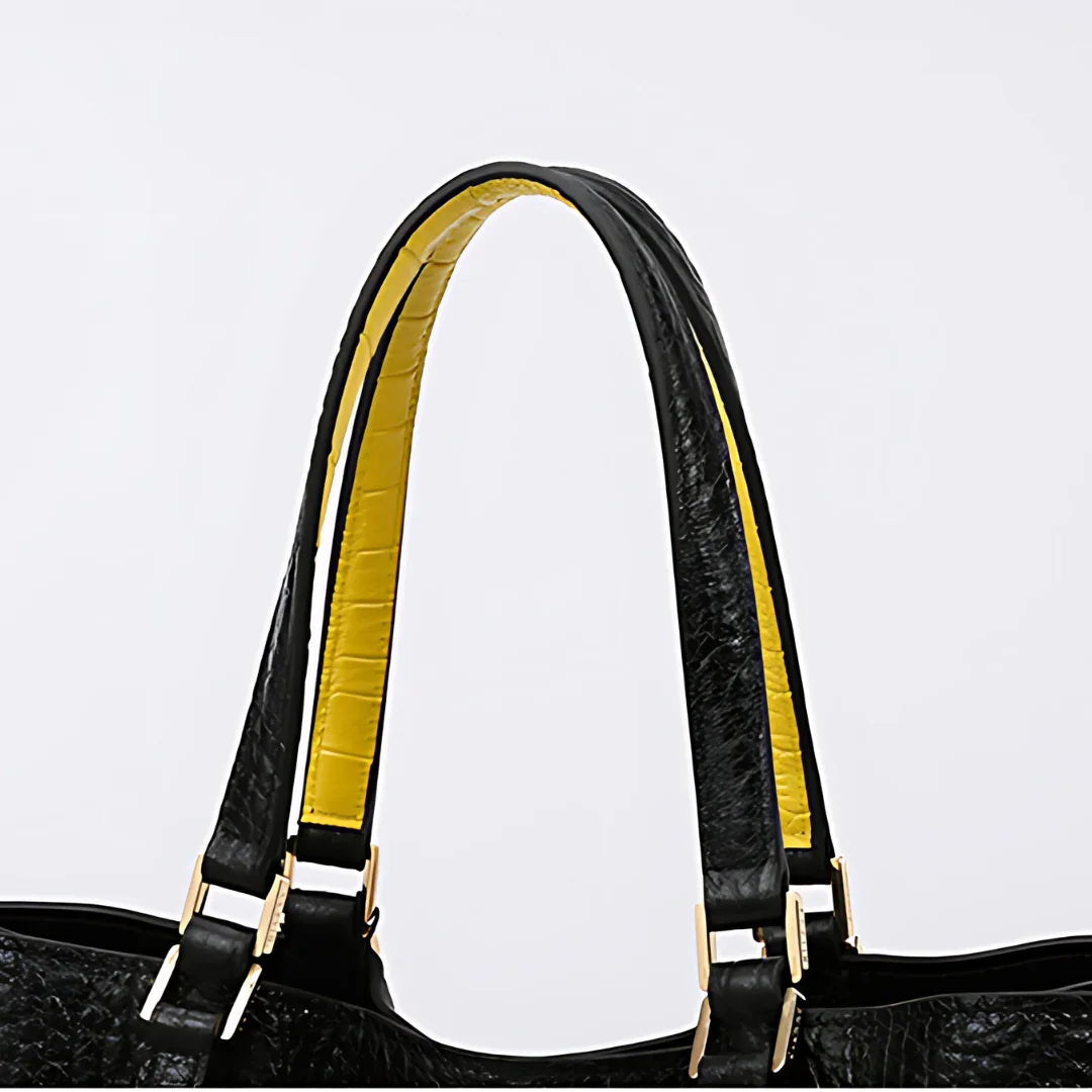 Black handbag with yellow inner straps and gold hardware on white background