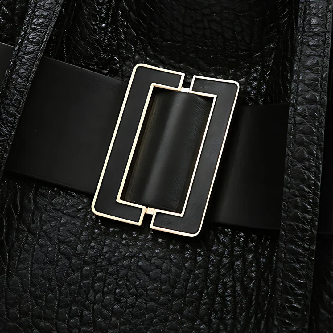 Close-up of black leather bag with rectangular gold buckle and textured finish