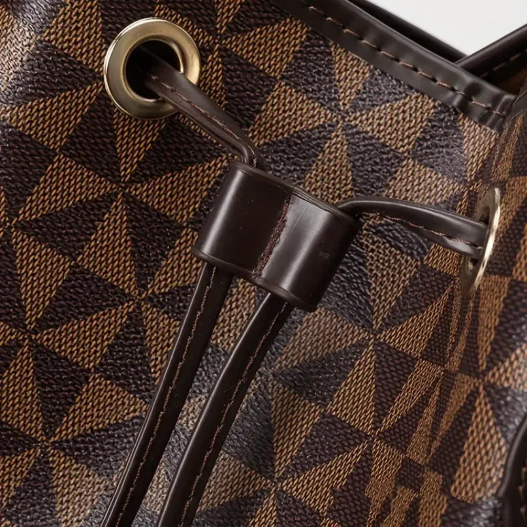 Close-up of brown geometric leather bag with gold eyelets and dark drawstring.