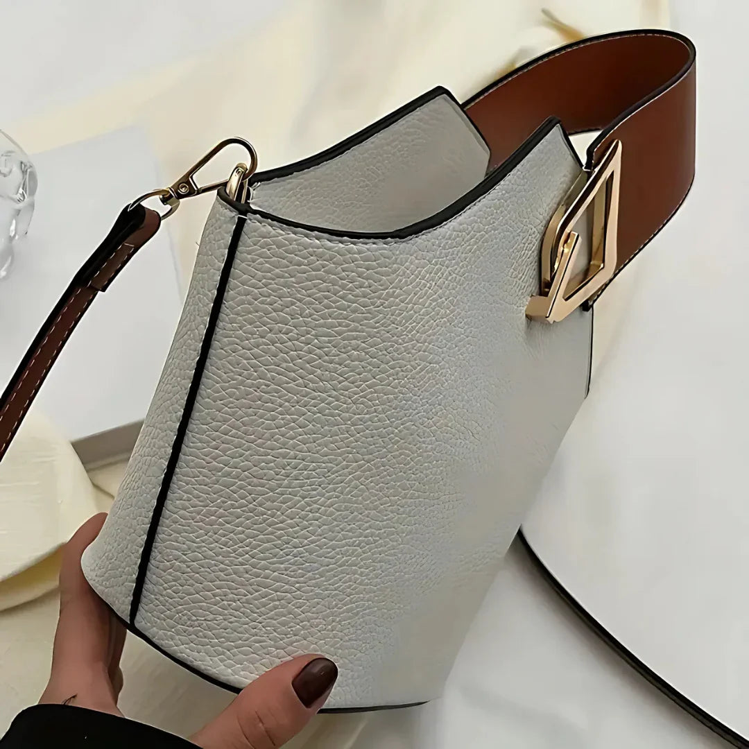 Textured white leather handbag with brown strap and gold buckle, modern minimalist design