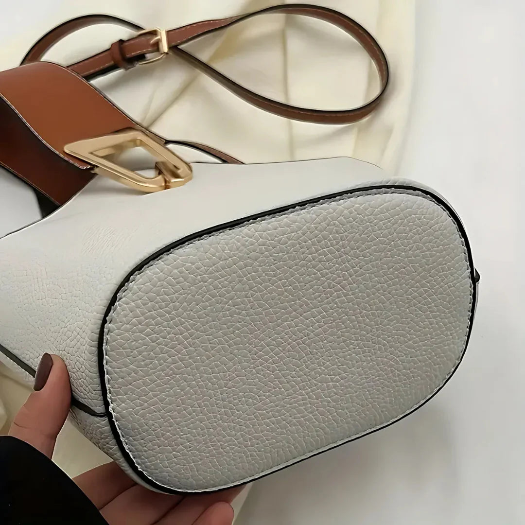 Close-up of white textured leather handbag with brown strap and gold buckle