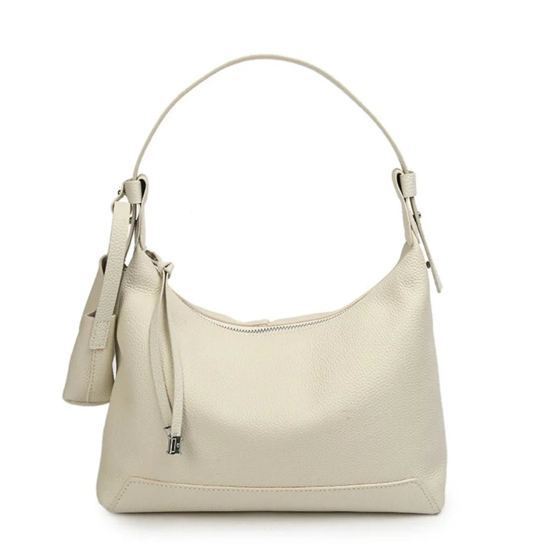 Beige leather shoulder bag with single strap and zip closure on white background