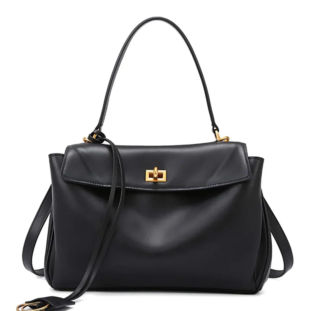 Black leather handbag with gold hardware and top handle on white background