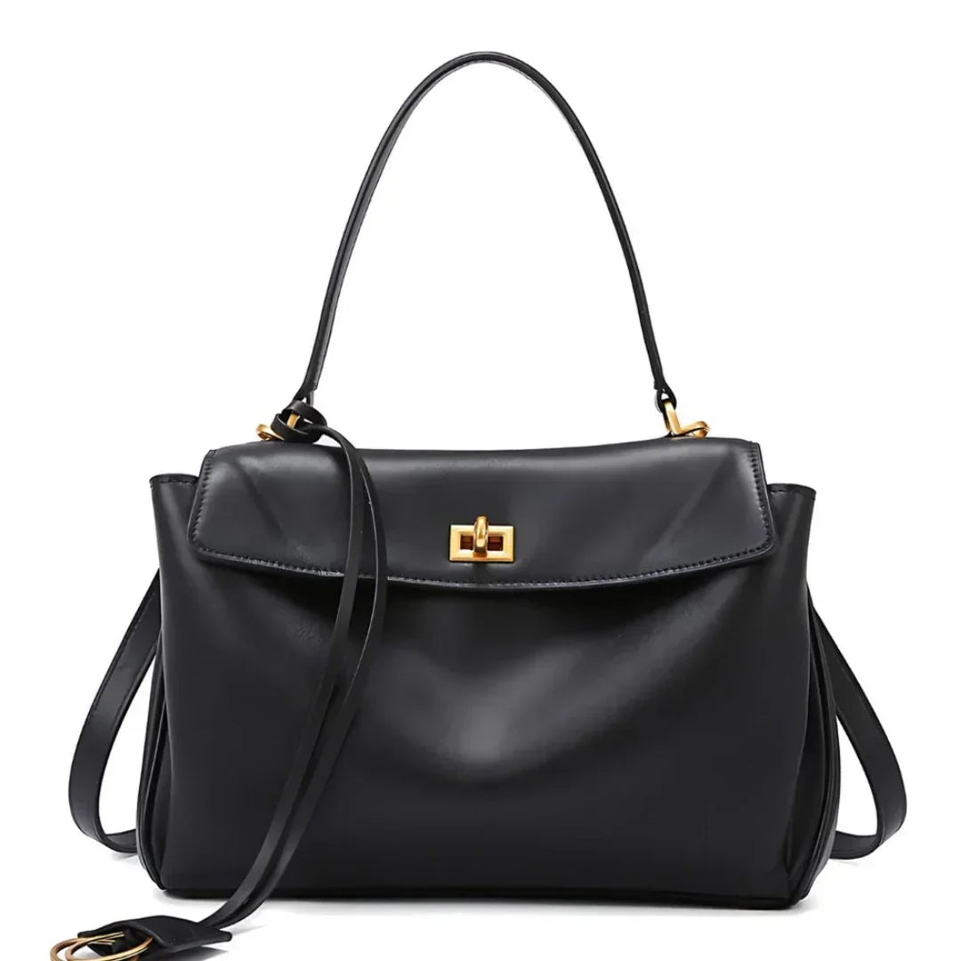Black leather handbag with gold hardware and top handle on white background
