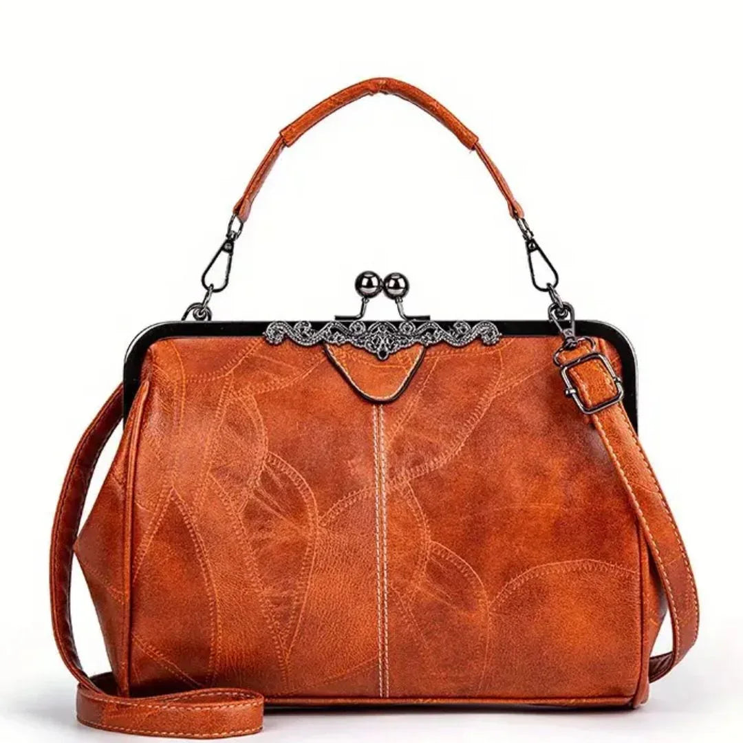 Vintage brown leather handbag with floral stitching and metal clasp, isolated on white.