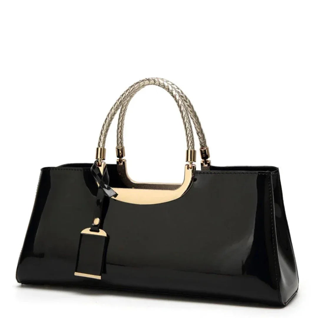 Glossy black handbag with gold handles and braided straps on white background