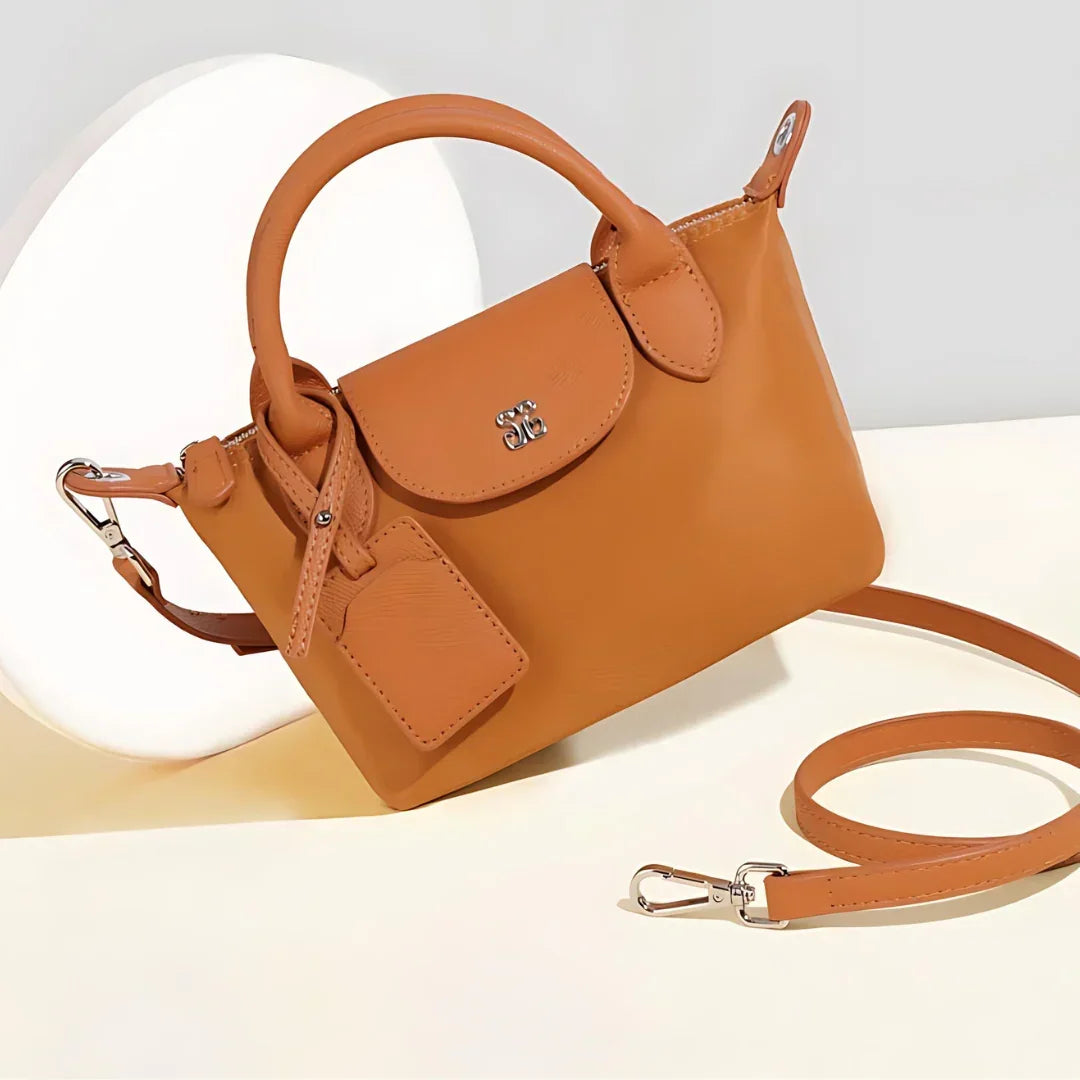 Tan leather handbag with detachable strap and silver hardware on light background