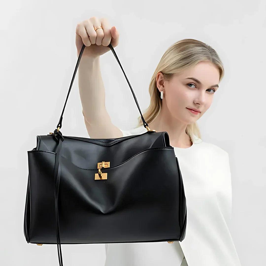 Woman holding black leather handbag with gold hardware against white background