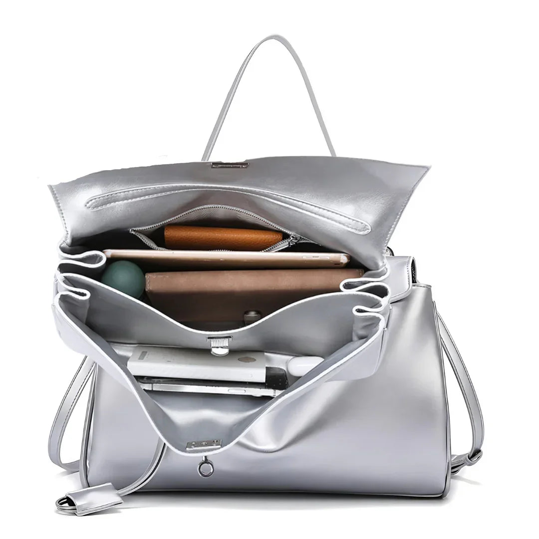 Open silver tote handbag with organized compartments holding gadgets and accessories