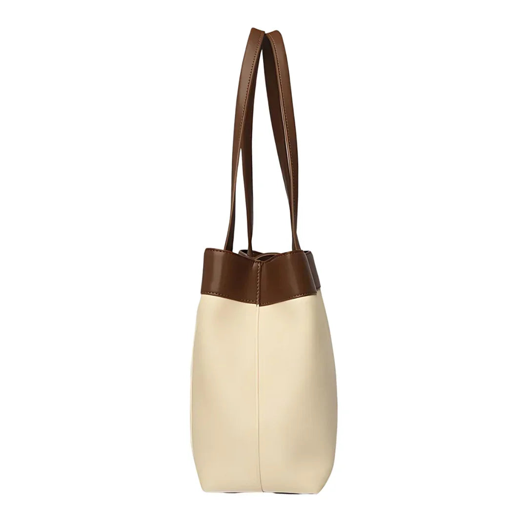 Side view of a beige and brown leather tote bag with double handles