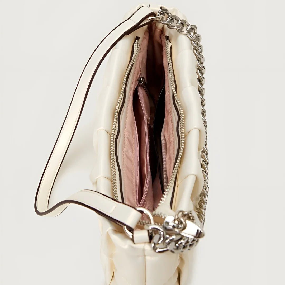 Top view of cream quilted purse with pink interior, zipper compartments, and chain strap