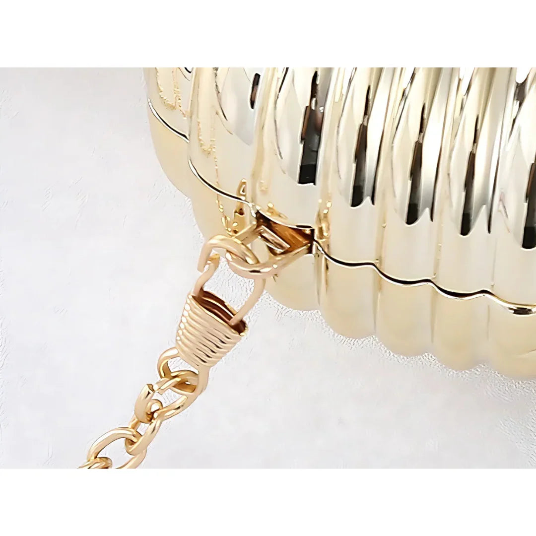 Close-up of gold metallic clutch purse with ribbed texture and chunky chain strap