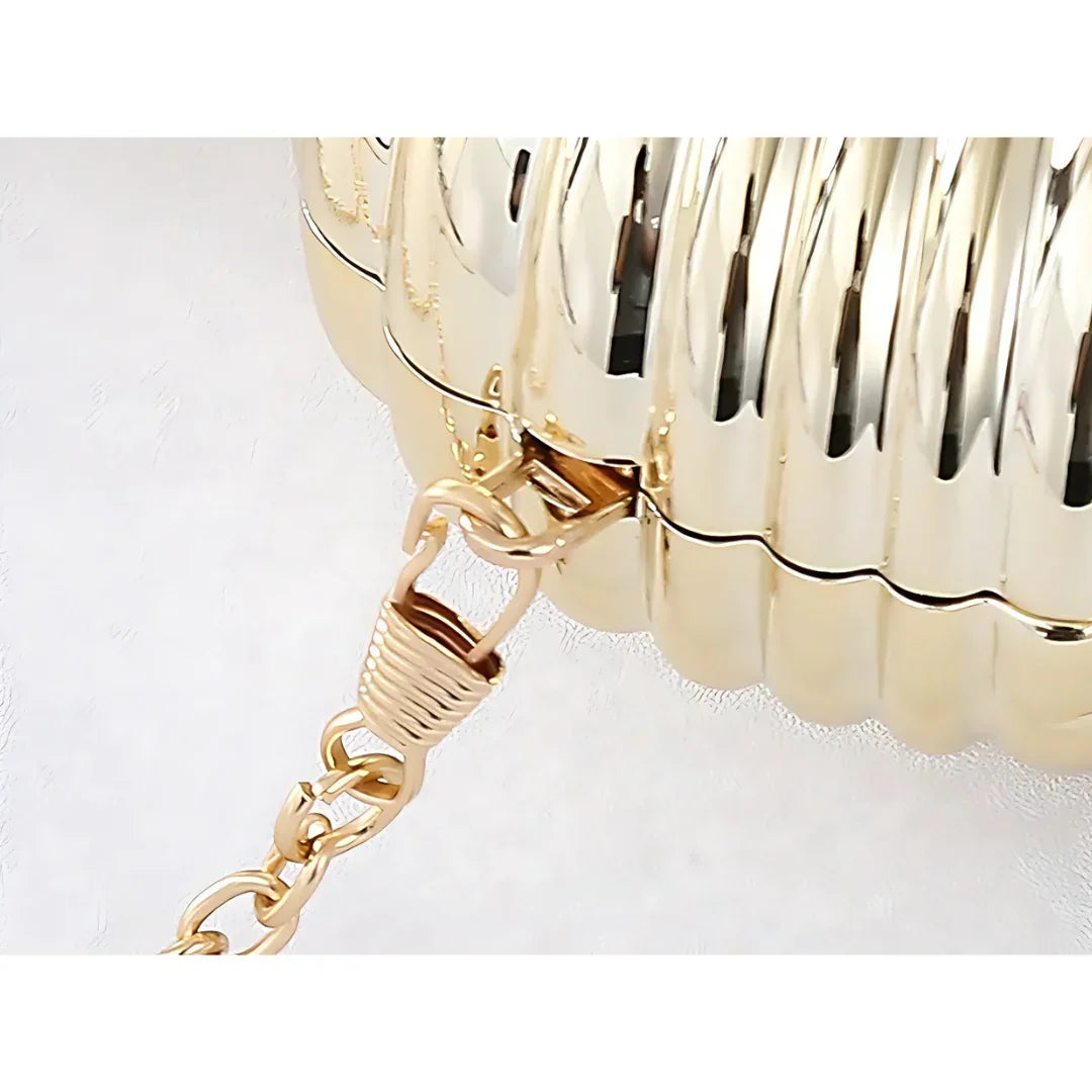 Close-up of gold metallic clutch purse with ribbed texture and chunky chain strap