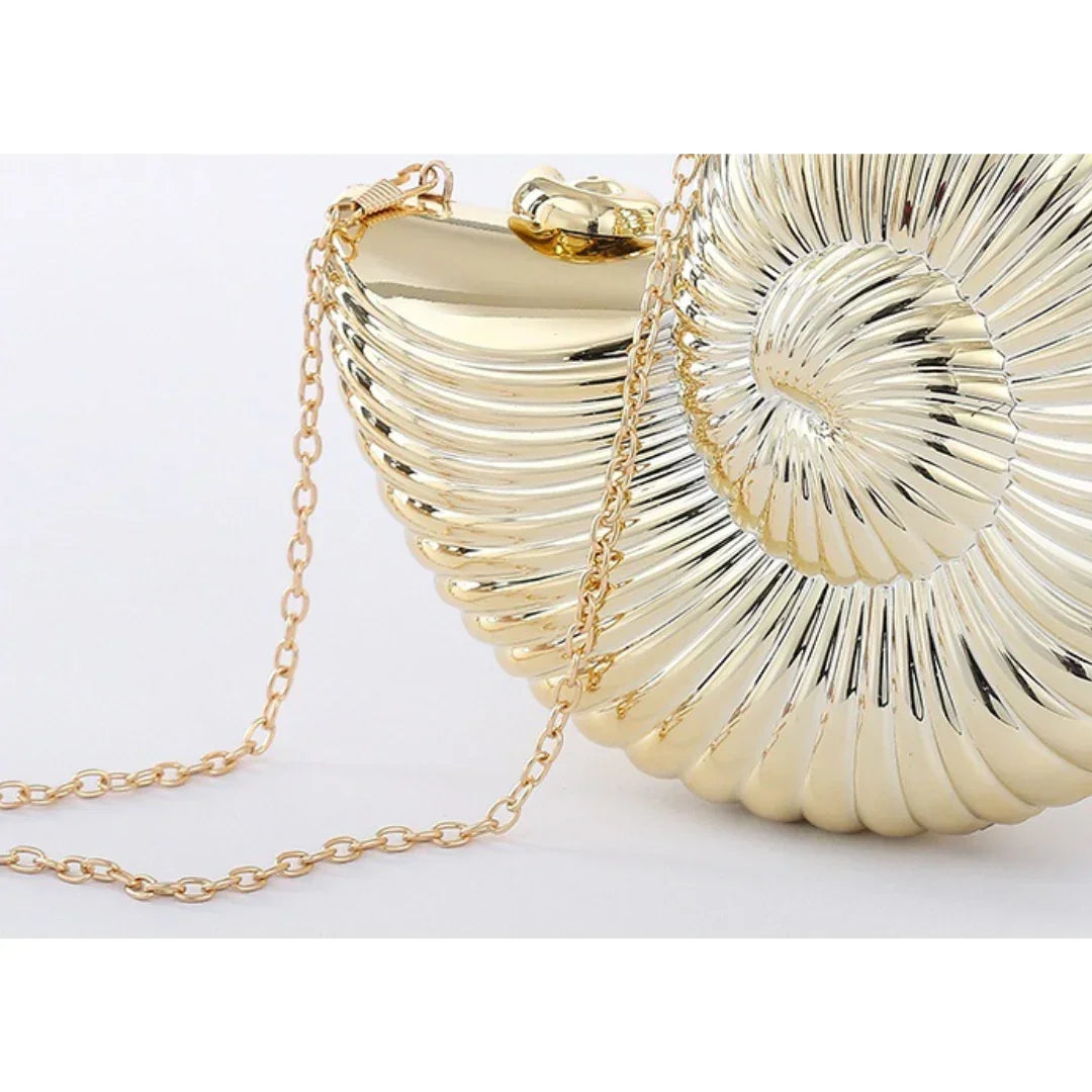 Gold seashell clutch purse with shiny metallic finish and gold chain strap on white background