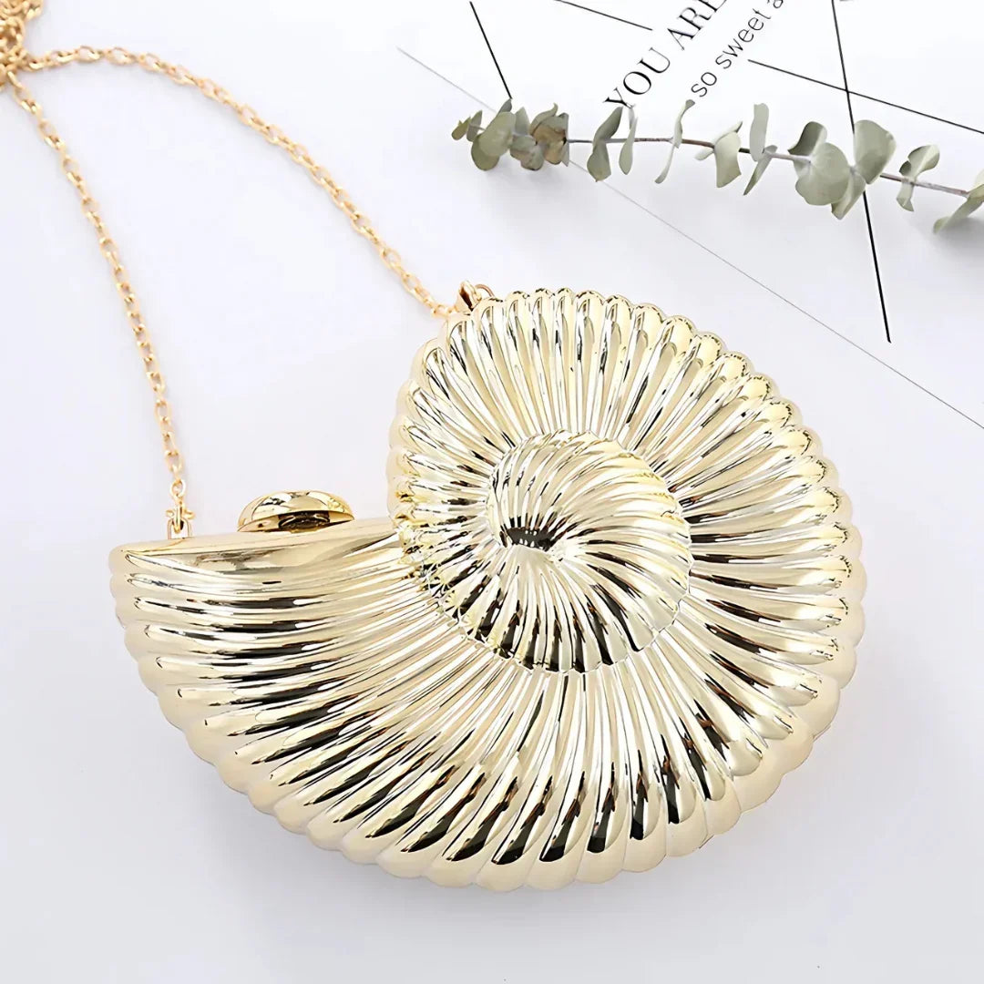 Gold seashell-shaped clutch bag with chain strap on white background, modern accessory