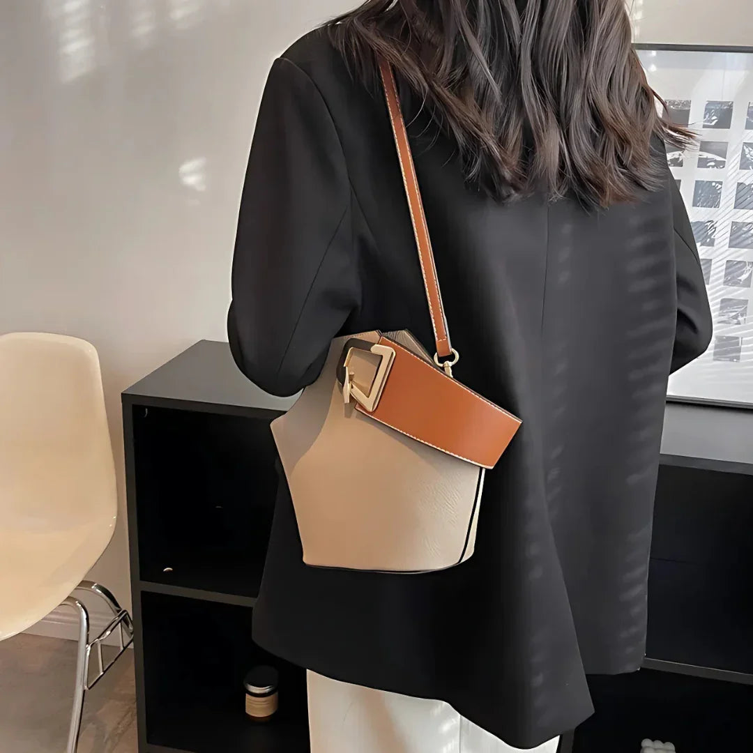 Woman in black blazer with beige bucket bag and brown strap in modern office setting