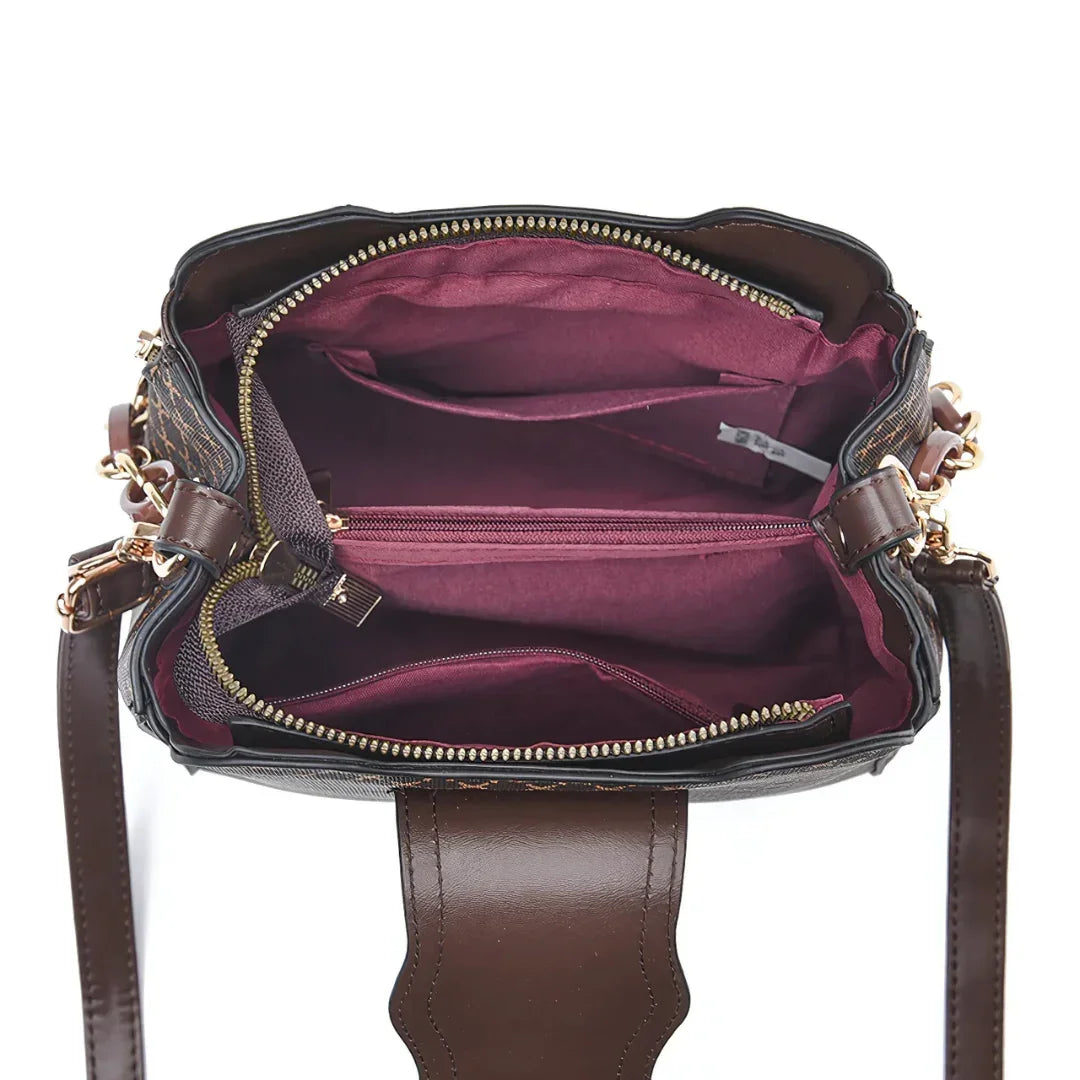 Open brown leather handbag with gold zippers and maroon fabric interior compartments