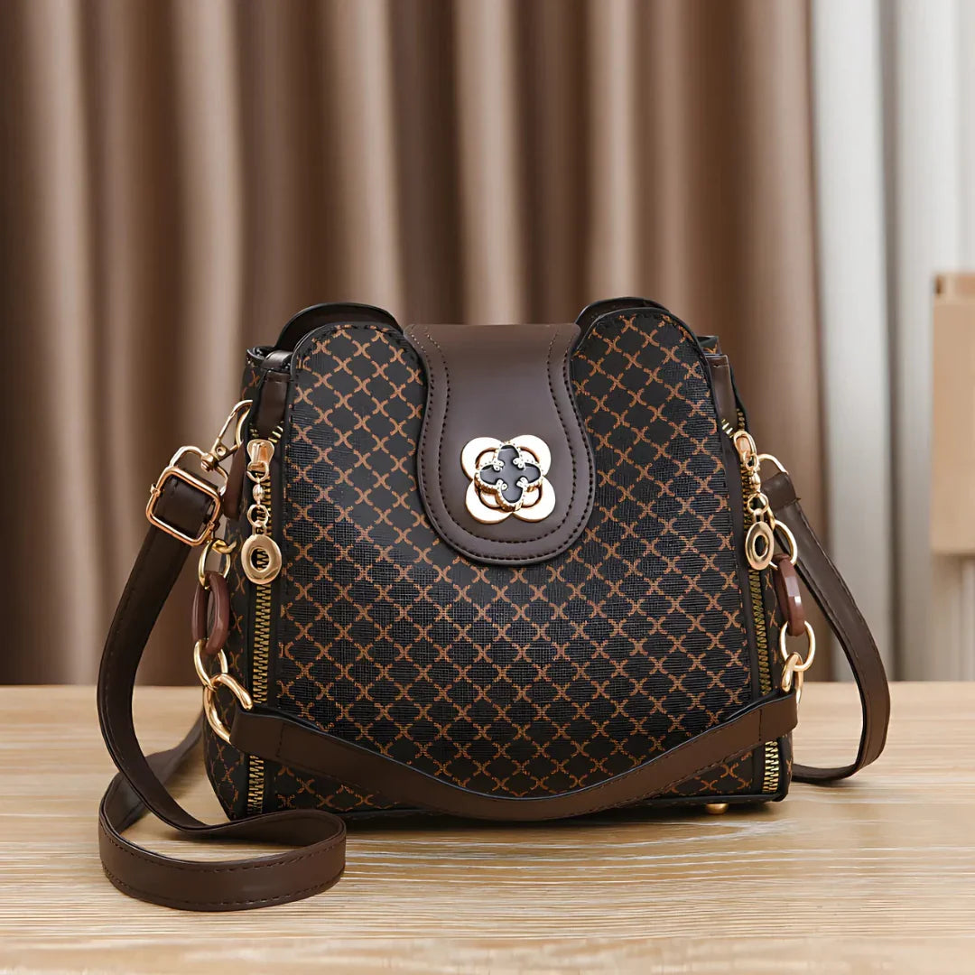 Brown leather designer handbag with gold hardware on wooden table