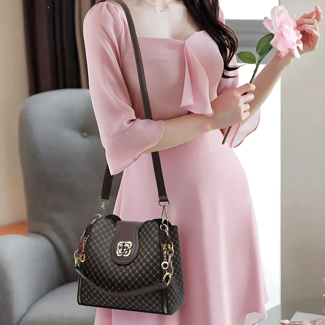 Woman in pink dress holding a pink rose and wearing a patterned shoulder handbag
