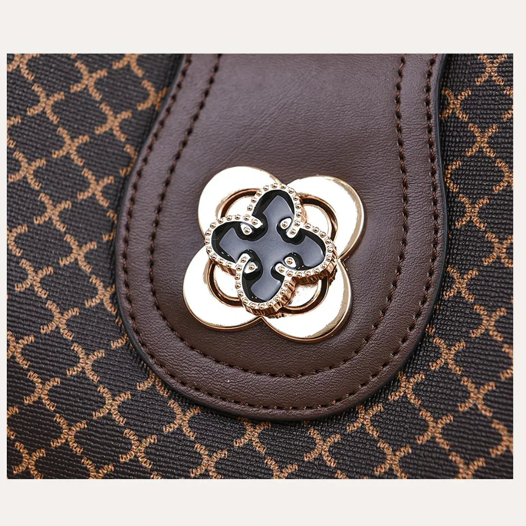 Brown leather handbag closeup with gold floral clasp and geometric pattern
