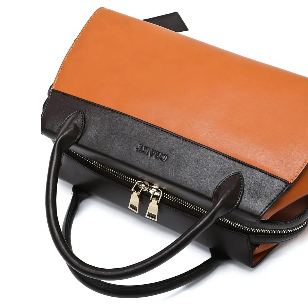 Two-tone leather handbag with brown flap, black handles, and gold zipper detail