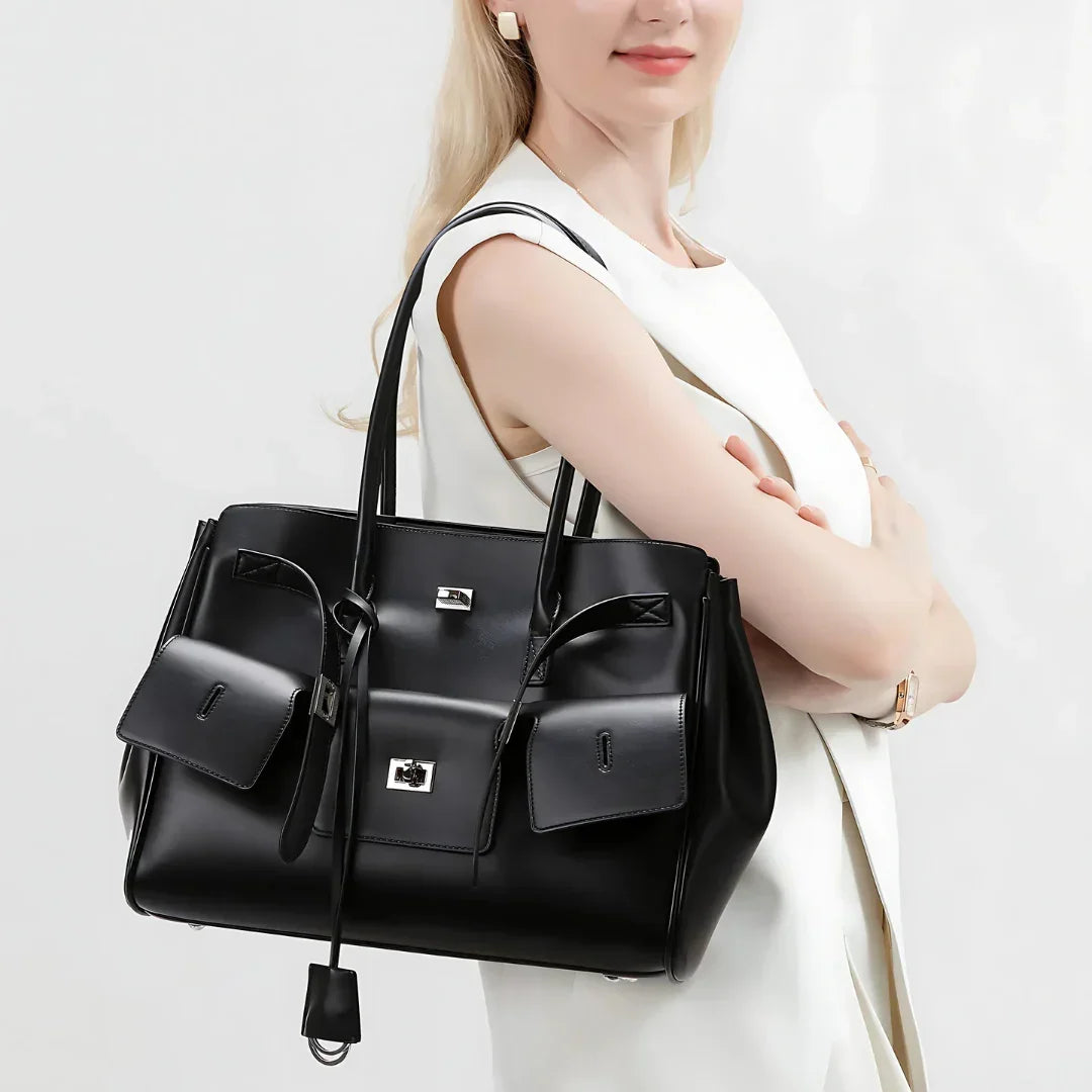Woman carrying a black leather tote bag with silver hardware and front pockets