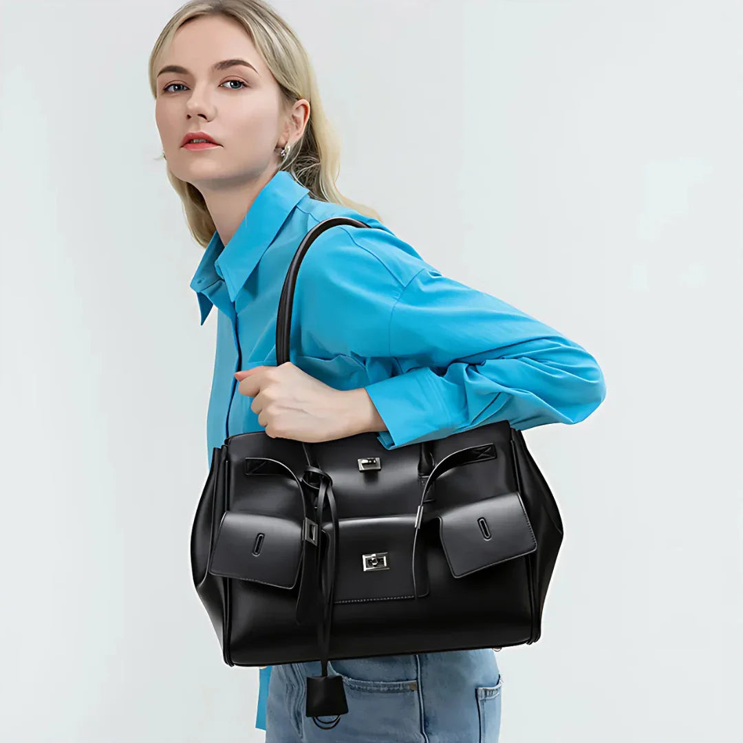 Woman in blue shirt carrying large black leather handbag with front pockets