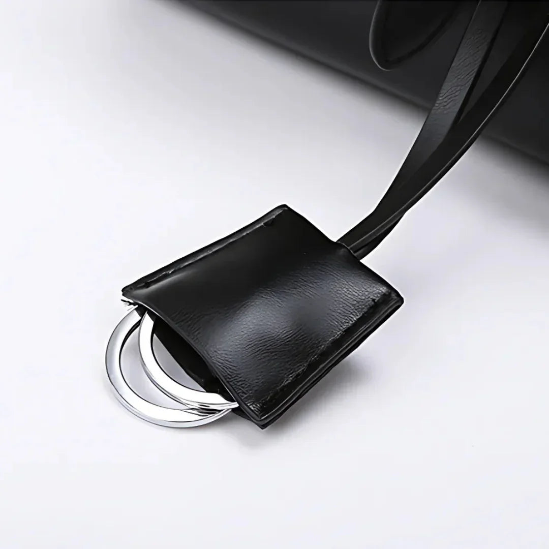 Black leather bag with silver metal ring keychain detail on white background