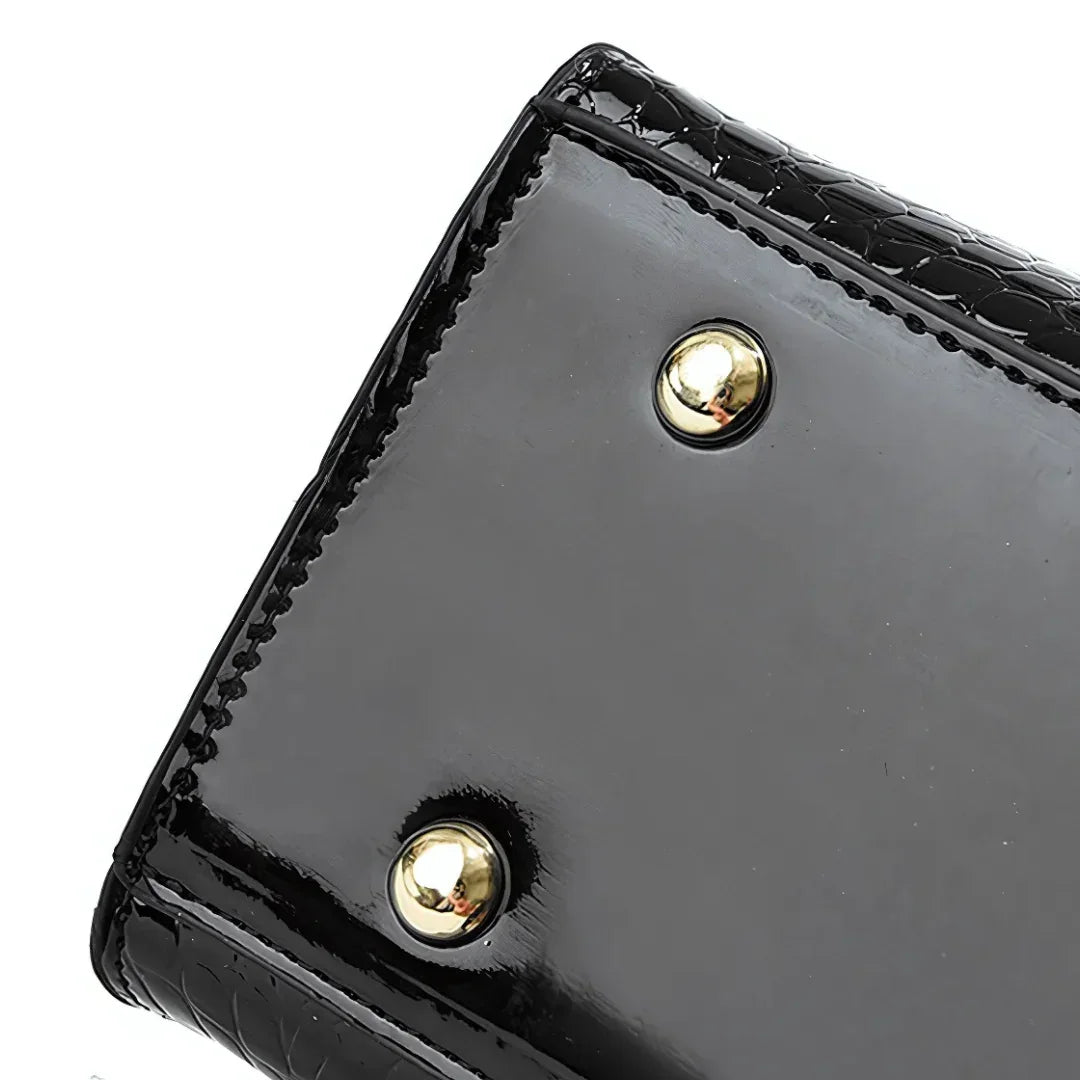 Glossy black purse bottom with gold metal feet, textured edge detail