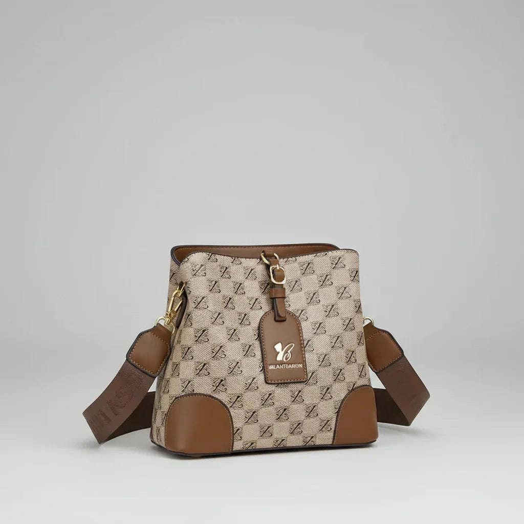 Beige and brown leather crossbody bag with logo pattern and adjustable strap on gray background