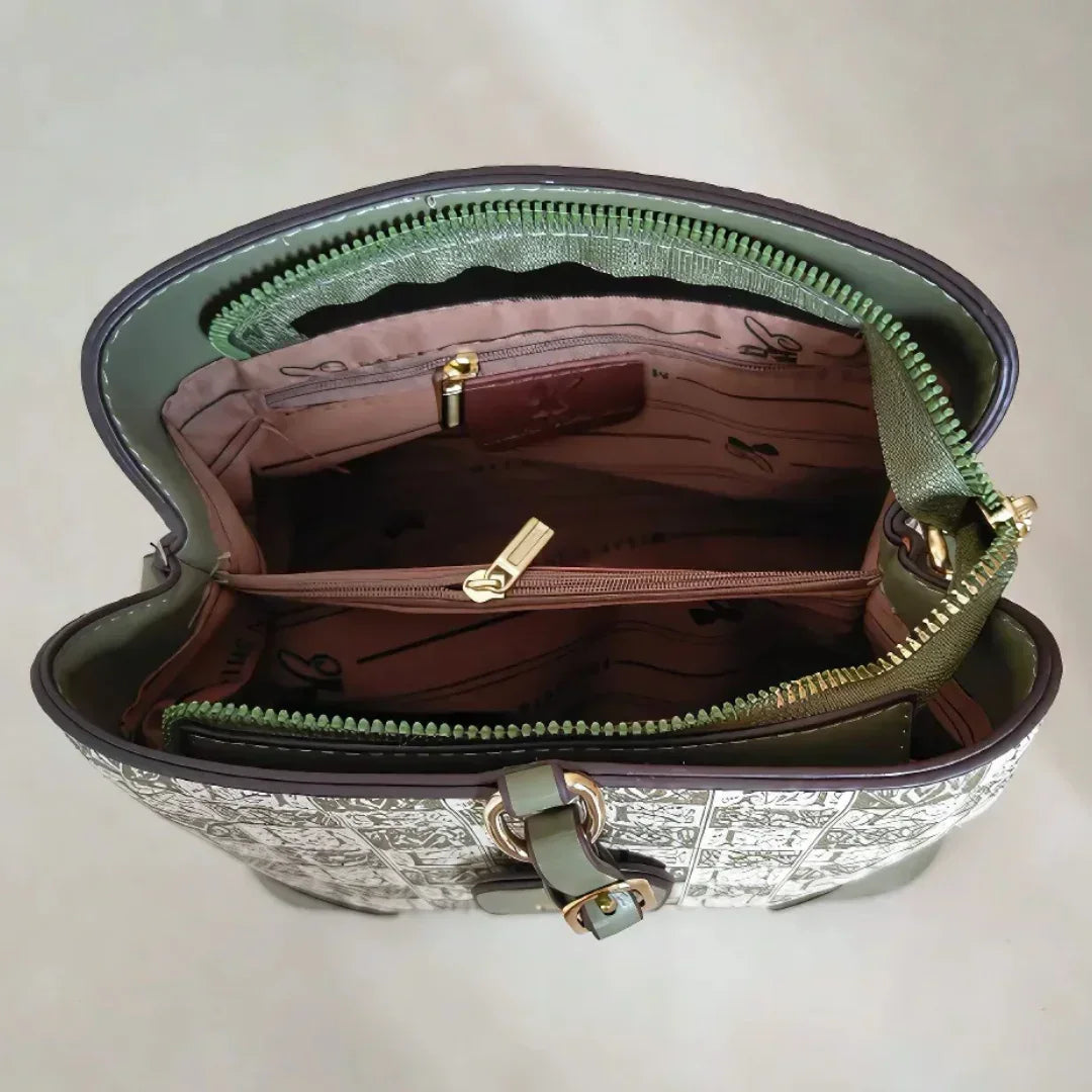 Top view of open designer handbag with patterned lining, gold zippers, and green trim