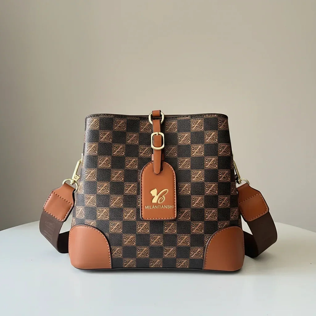 Brown checkered Milantianshi handbag with gold buckle and leather strap on white table