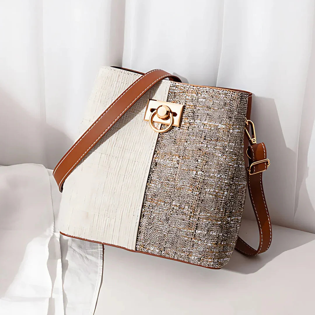 Elegant two-tone crossbody bag with tan strap, gold clasp, and textured fabric on white backdrop