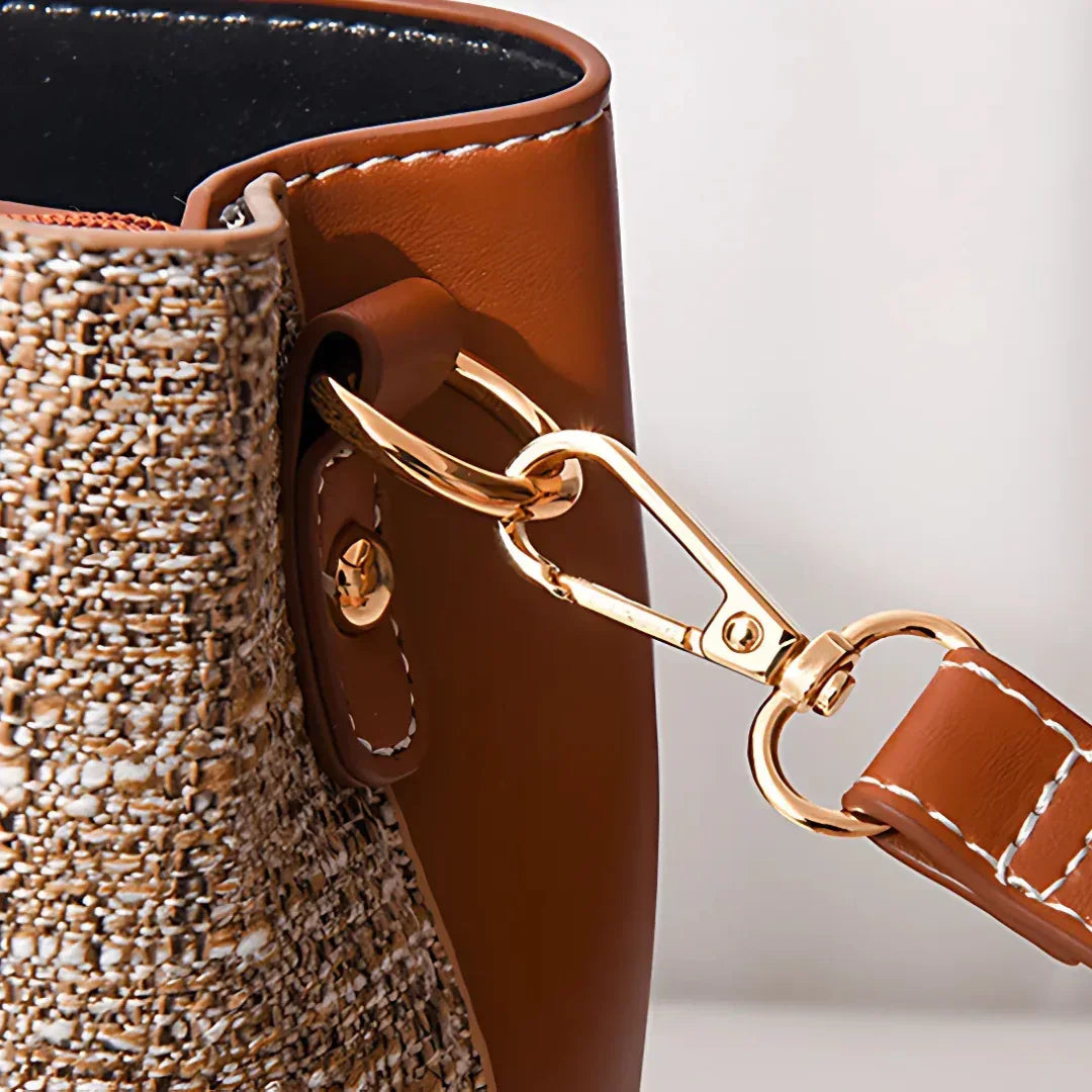 Close-up of brown leather and woven tote bag with gold metal clasp and stitching detail