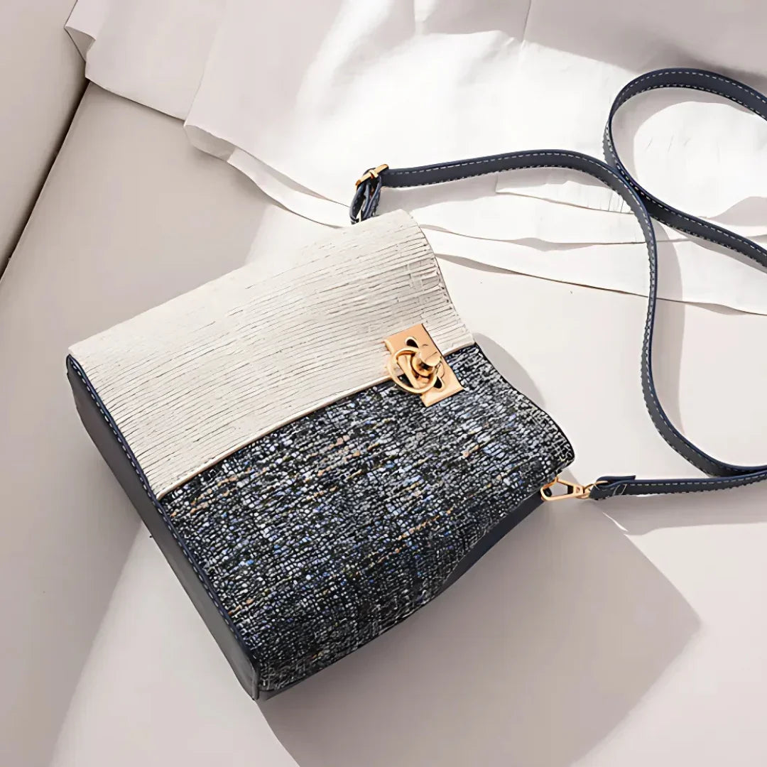 Elegant two-tone textured crossbody bag with gold clasp on a white fabric background