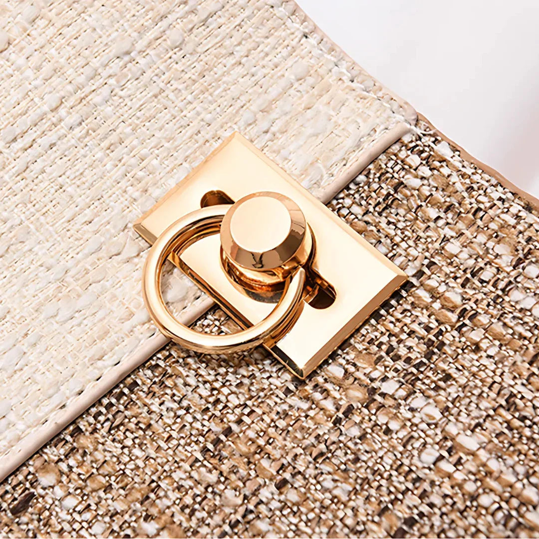 Close-up of gold metal clasp on textured beige tweed handbag